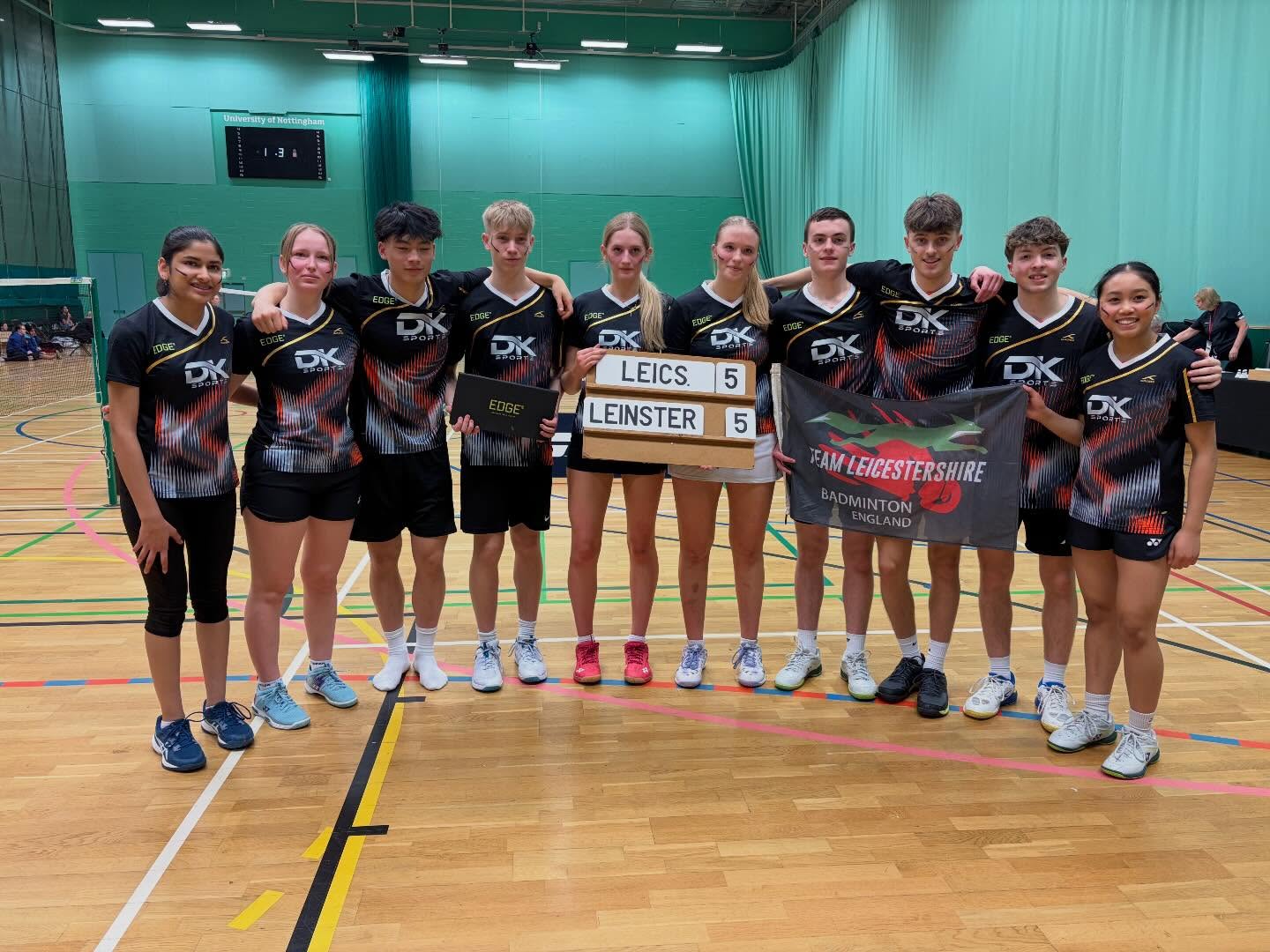 Team Leicestershire lined up on court in black DK kit with their team banner